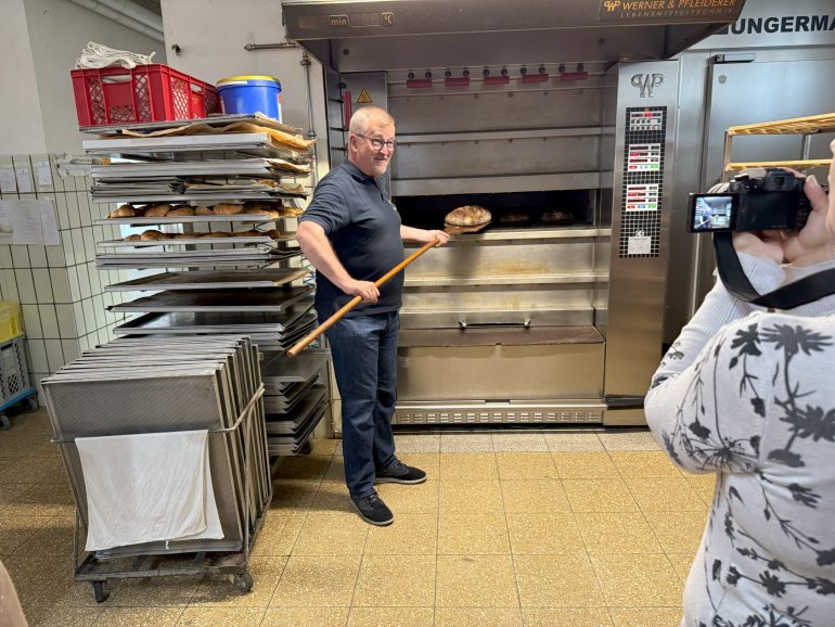 Bürgermeister Nickel holt ein fertiges Drei-Franken-Brot aus dem Ofen